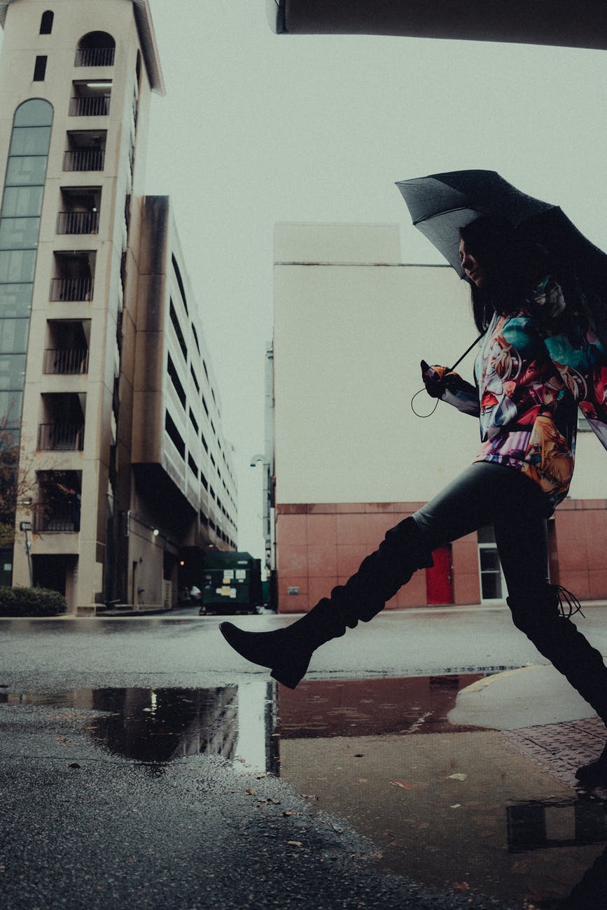 a woman holding an umbrella while walking on the street